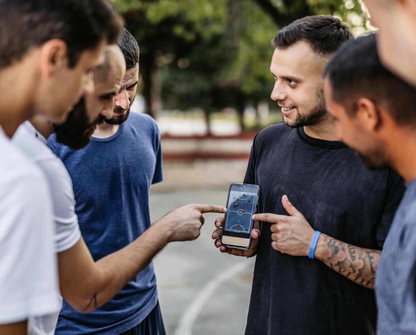 Un grupo de jugadores mira un partido en el celular antes de entrar a la cancha.